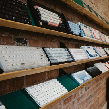 A variety of mechanical keyboards neatly displayed on a shelf in a brick-walled store interior.