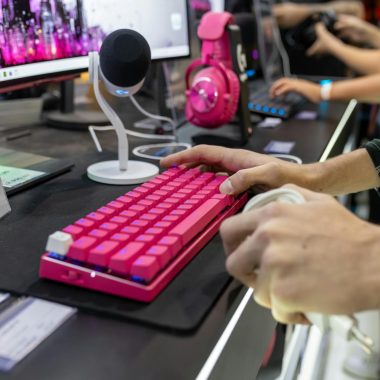 photo by matheus bertelli Close-up of a vibrant gaming setup featuring a pink keyboard and headset, ideal for streamers.