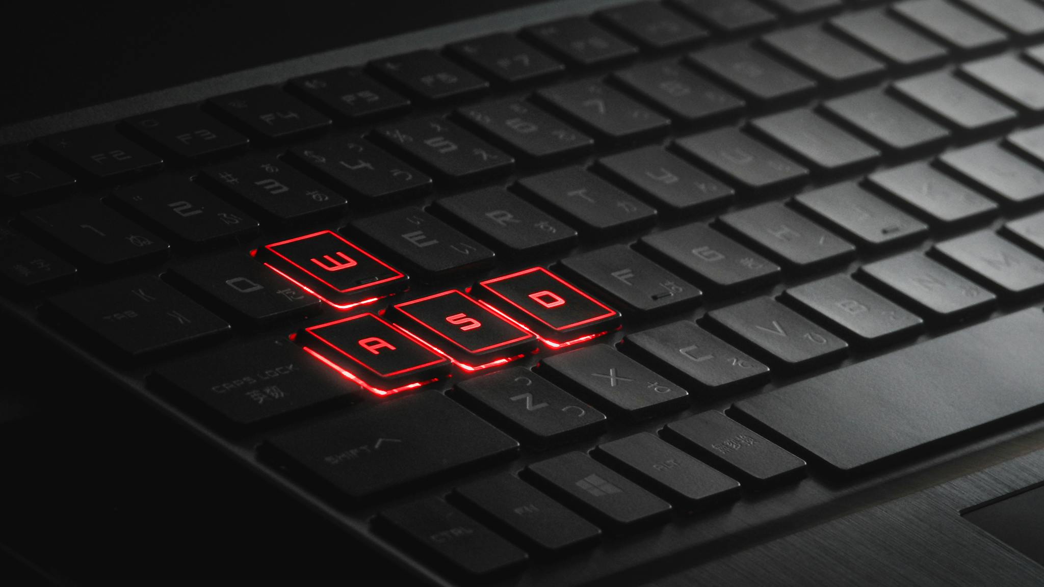 Home Close-up of illuminated WASD keys on a gaming keyboard with red LED lights.