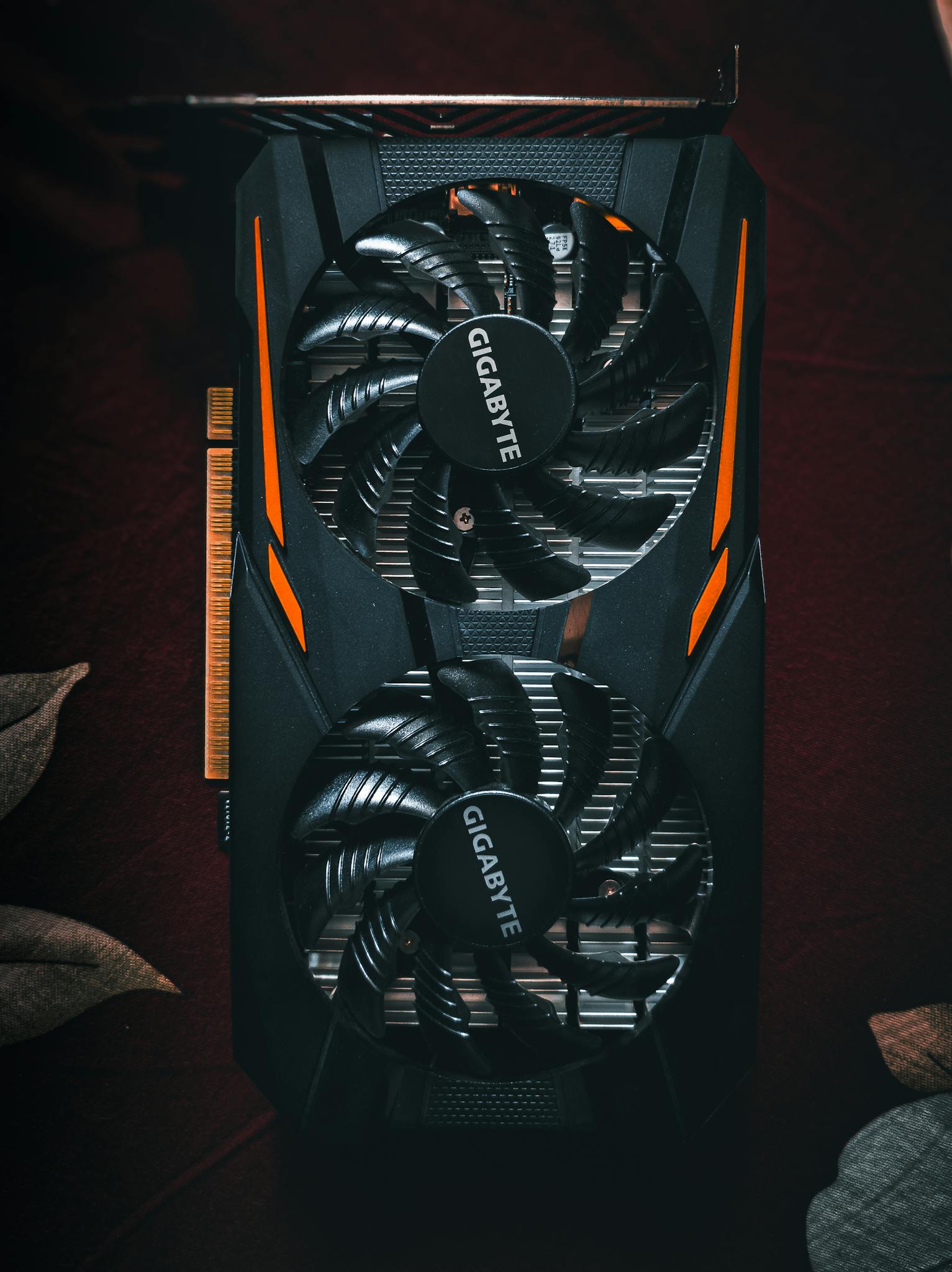 Home Detailed close-up of a black and orange graphic card with cooling fans.
