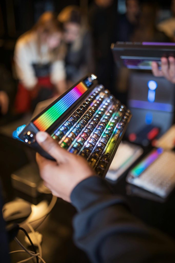 Person holding a vibrant RGB keyboard in a tech store setting with blurred background.
